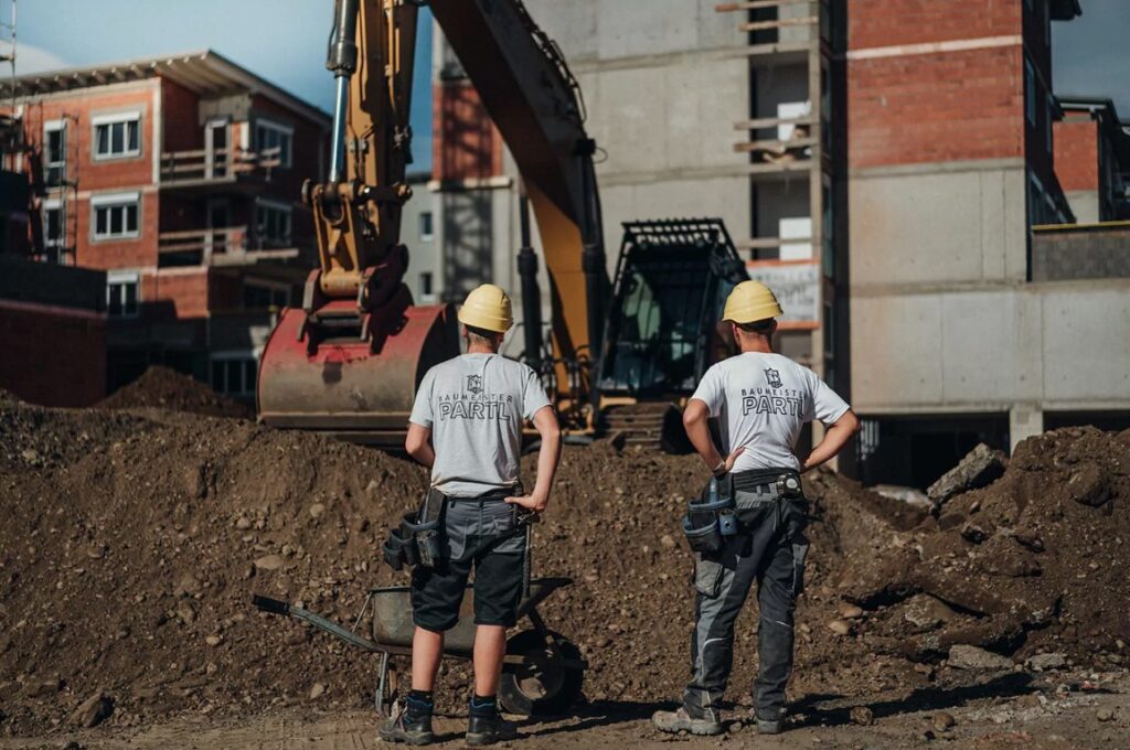 Zwei Bauarbeiter von Partl Bau machen Quereinsteiger Jobs auf einer Baustelle in Leibnitz