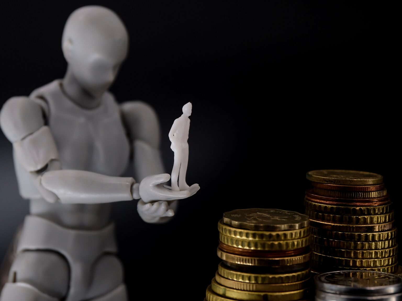 Roboter mit einer Figur in der Hand steht vor Geldmünzen
