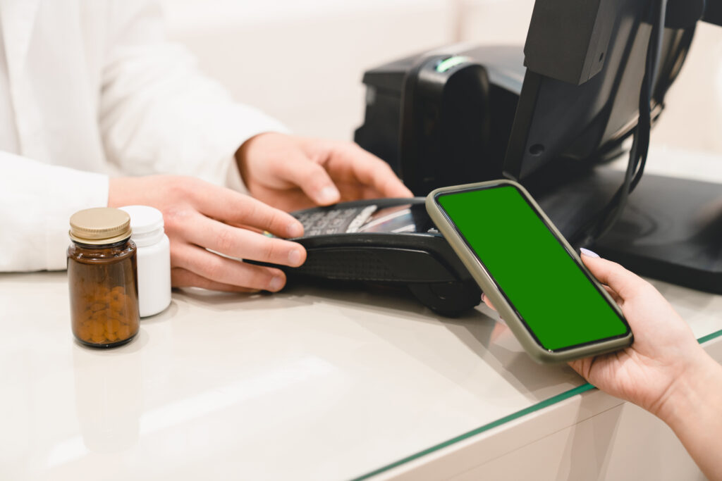 Handy mit grünem Hintergrund vor einem Bankomaten