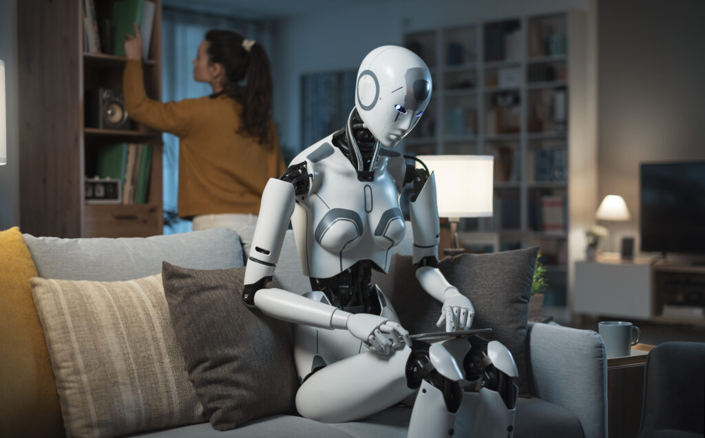 Roboter sitzt an einem Tag und eine junge Frau steht dainter