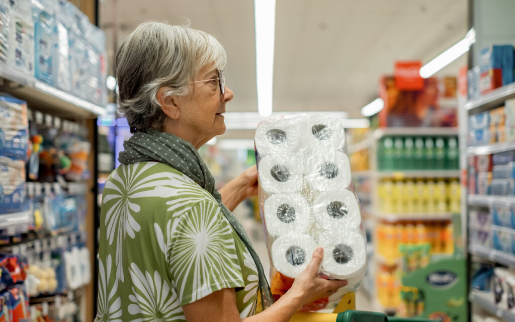 Ältere Frau hält eine Packung Toilettenpapier in der Hand