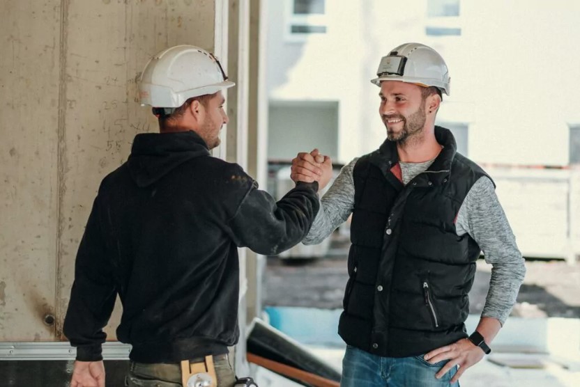 Zwei Bauarbeiter von Partl Bau machen einen Job als Quereinsteiger und reichen sich die Hände