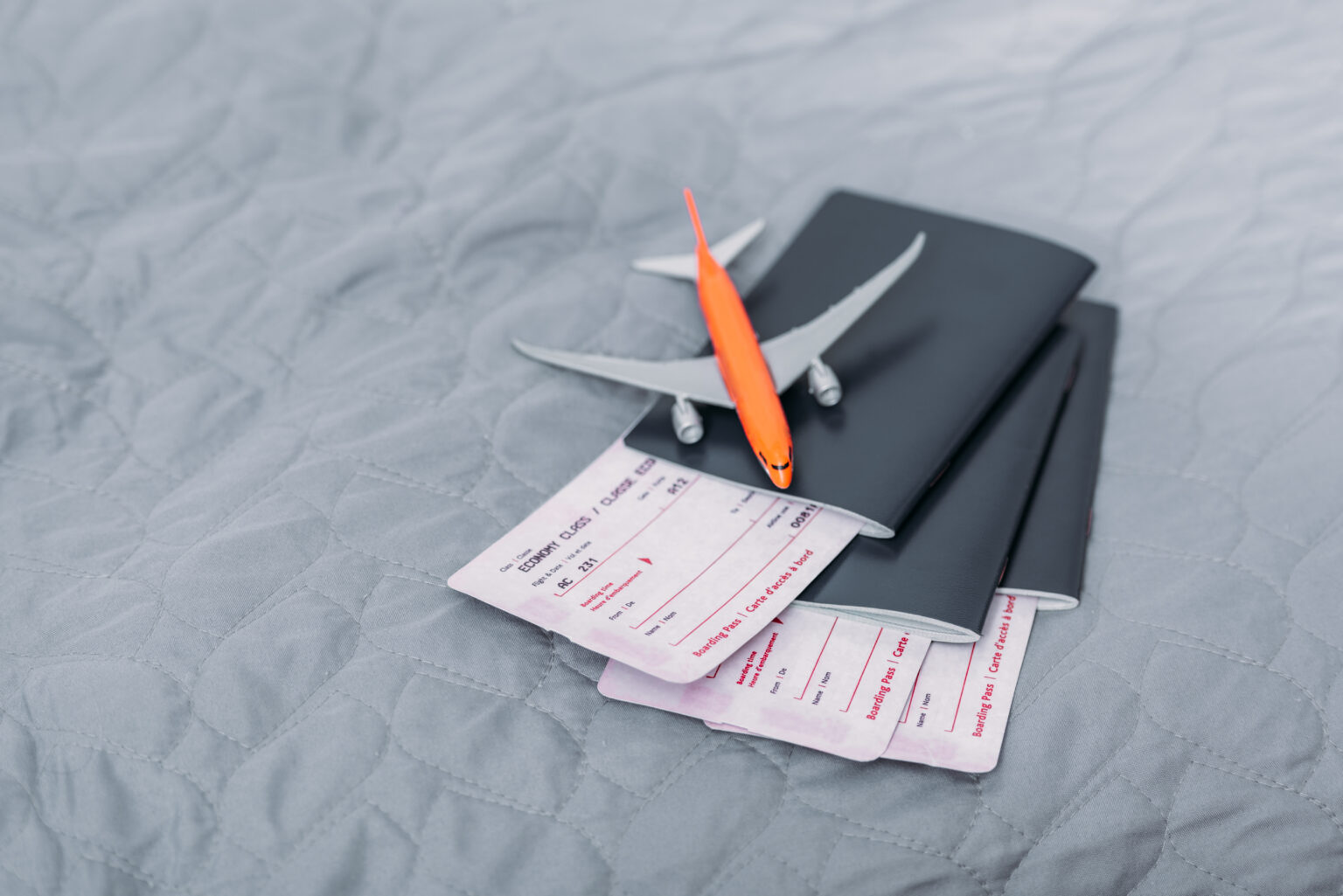 Grauer Tisch auf dem zwei Flugtickets liegen die in zwei Passports stecken. Darauf ein kleines Spielzeugflugzeug