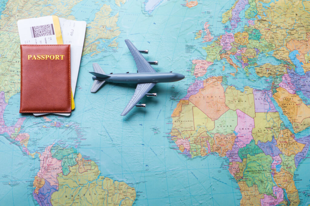 Weltkarte auf der ein Flugzeug aus Plastik liegt und ein Passport mit zwei Flugtickets