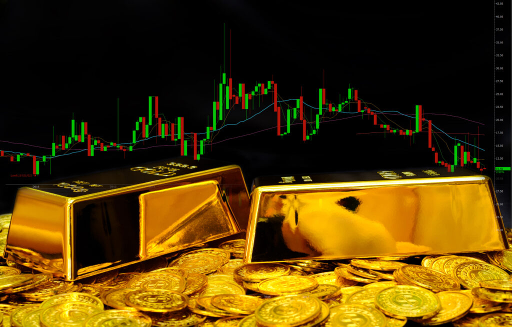 Aktienkurse in grün und rot. Davor liegen zwei große Goldbarren und viele goldene Münzen
