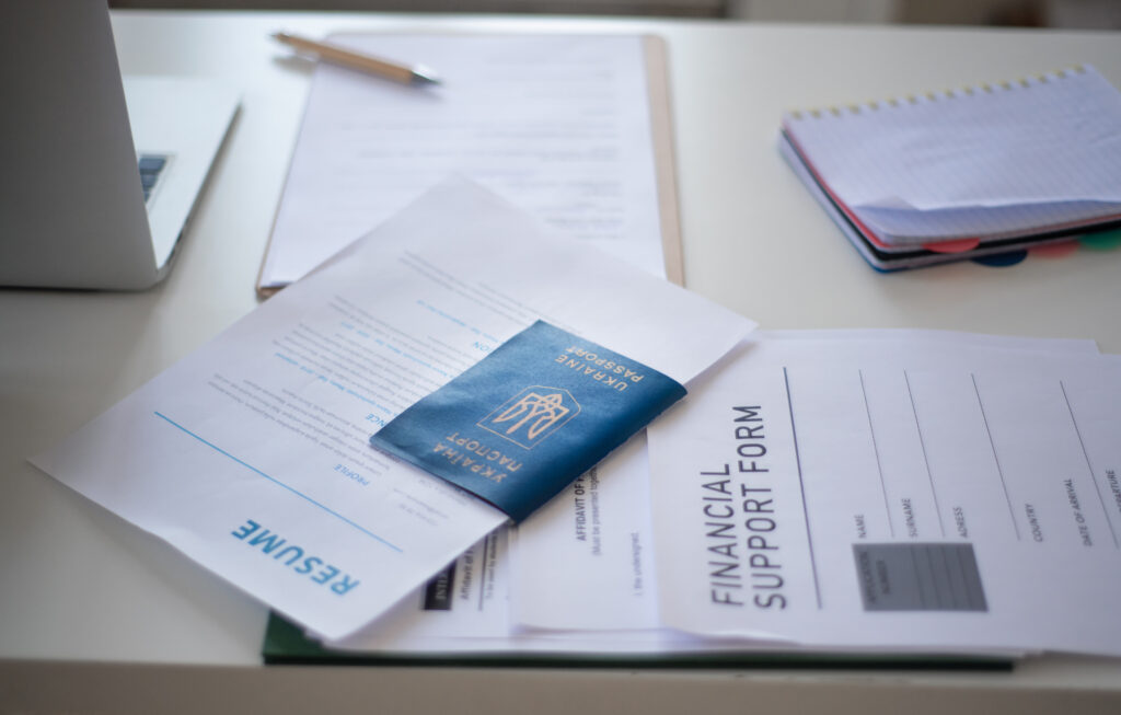 Ein Reisepass der ein Formular enthält liegt mit anderen Dokumenten auf einem Tisch