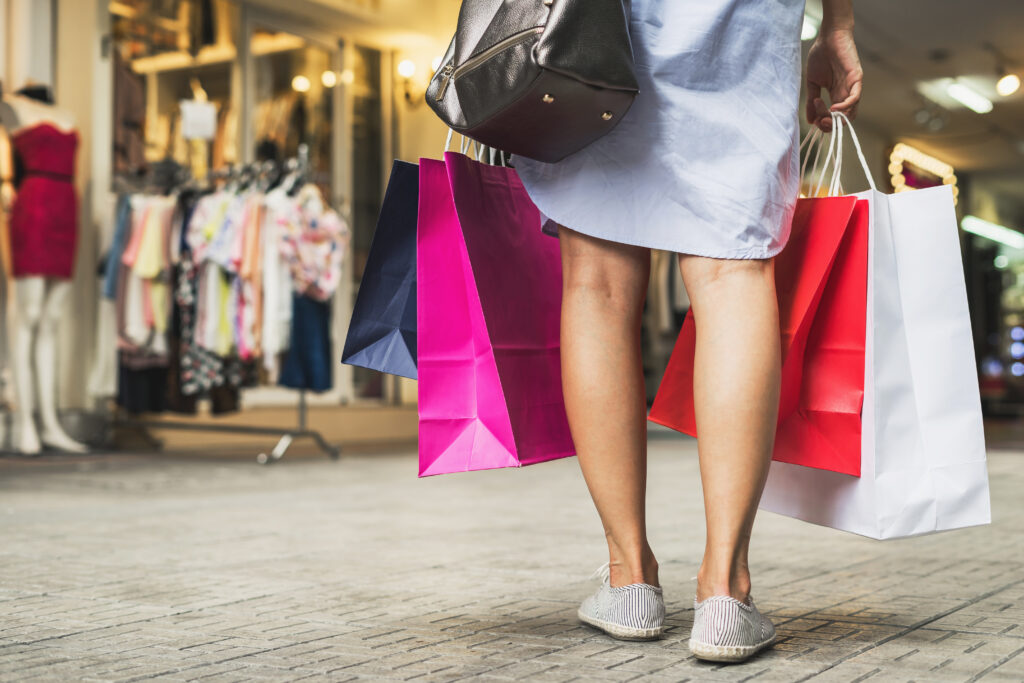 Frau trägt mehrere Shoppingtüten mit sich