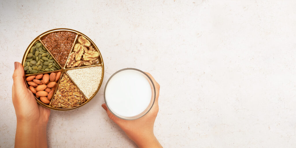 Glas Milch und verschiedene Proteine in einem Holzgefäss