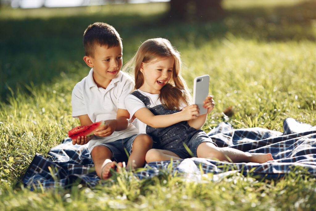 Kinder spielen mit HAndy im Park