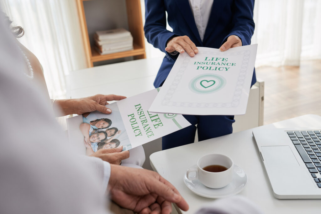 Mann mit Anzug hält ein Dokument über Life Insurance Policy und eine Frau hält eine andere Unterlage dazu 