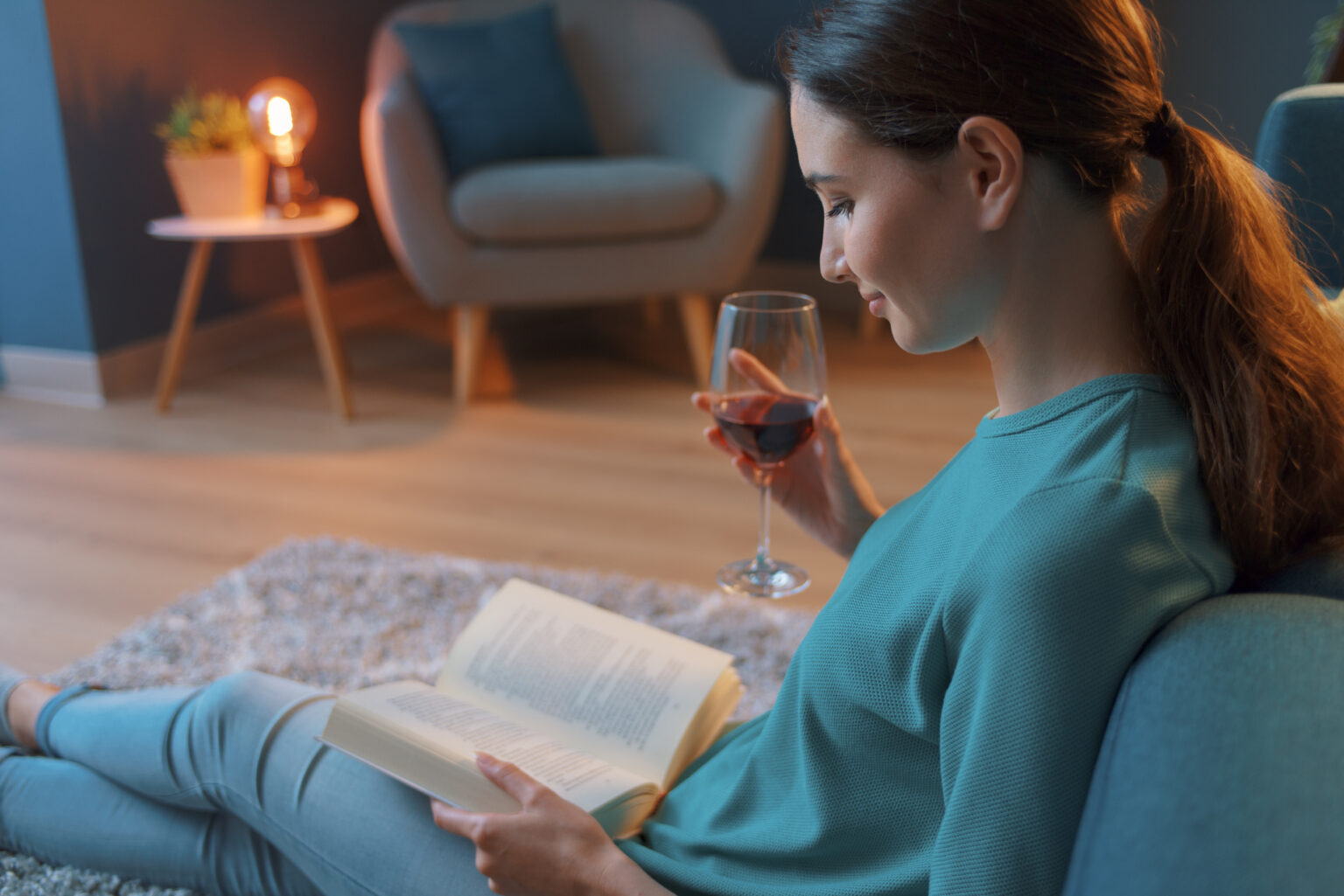 Frau liest ein Buch und trinkt Wein