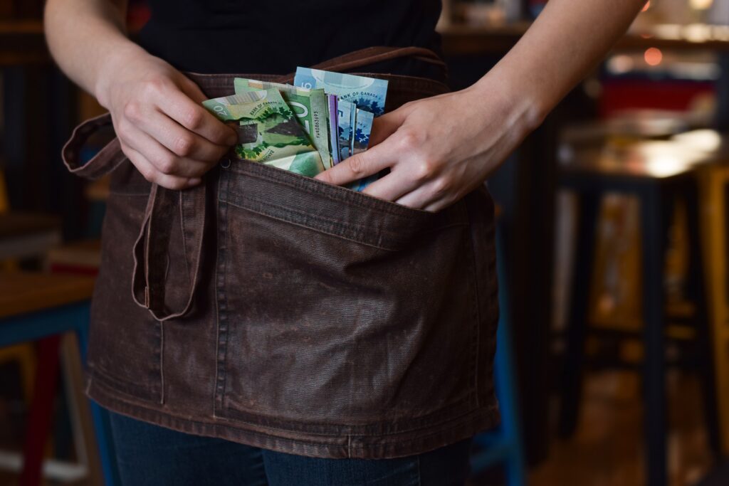 Handtasche mit Geldscheinen und eine Hand die hineingreift