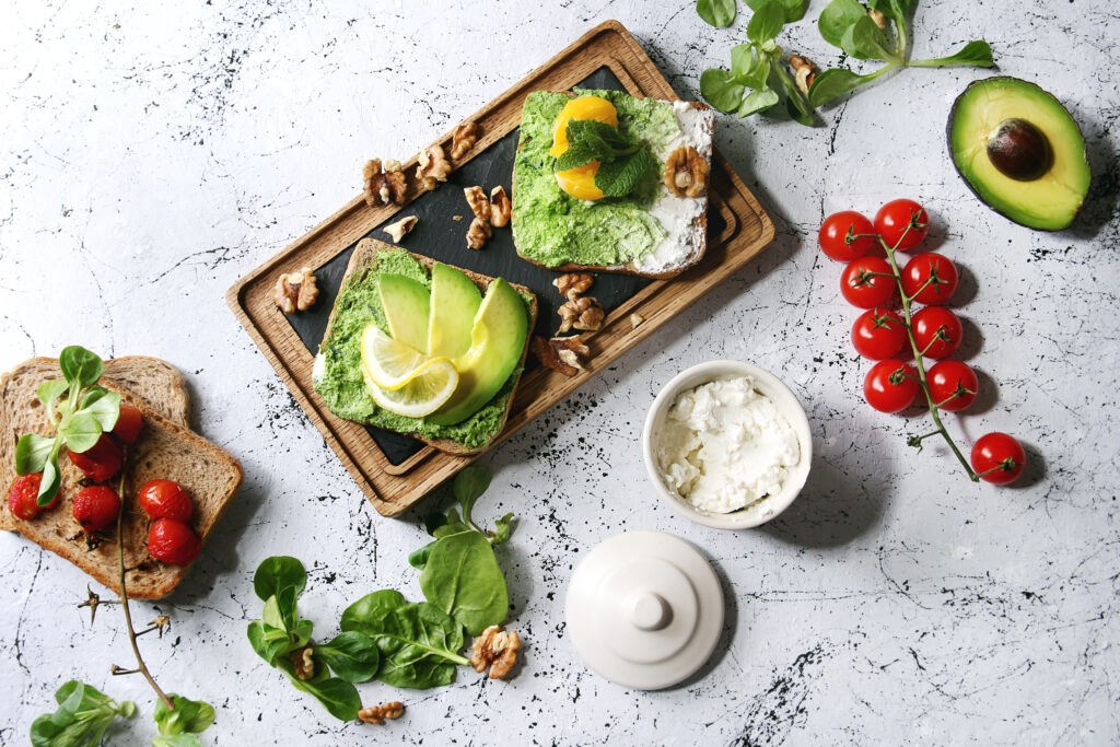 Zwei Produkte mit Avocado, Aufstriche und Tomaten auf einem Tisch