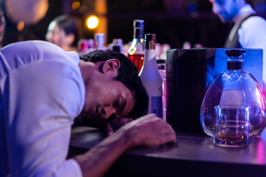 Betrunkener Mannn lehnt sich auf Bartisch