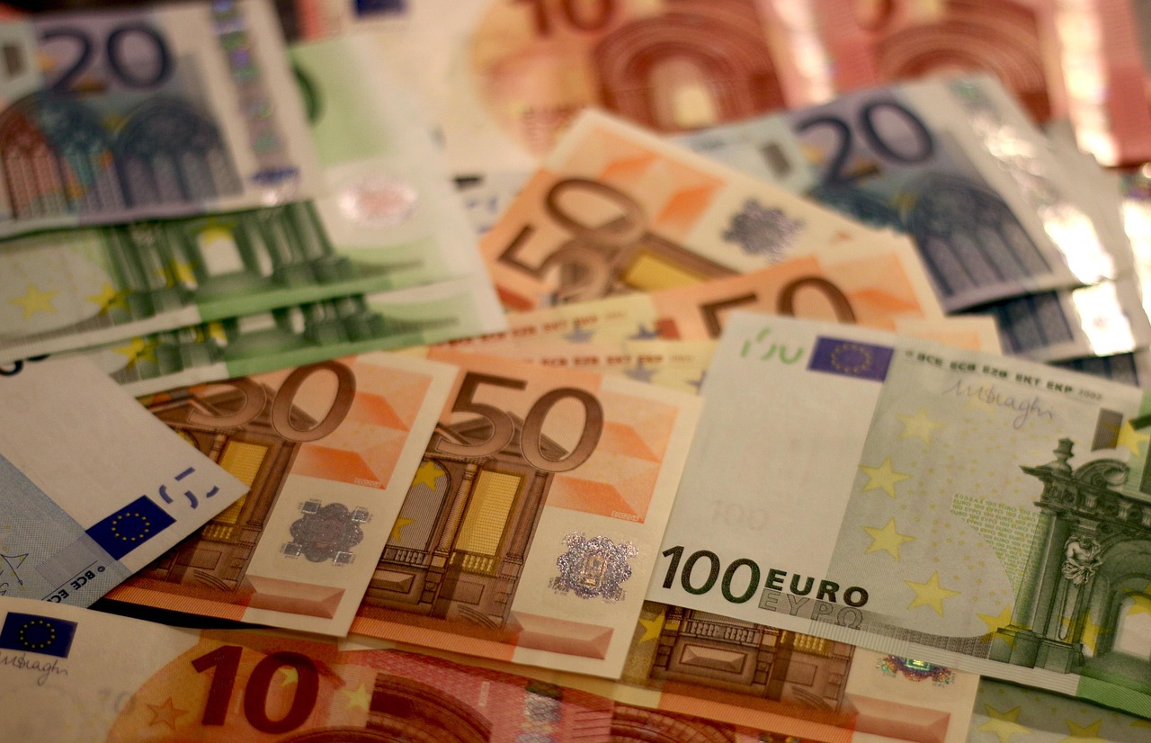 Ein Stapel Euro-Banknoten neben einer kleinen französischen Flagge auf einem Schreibtisch symbolisiert die hohen Frankreich Staatsschulden – Foto: moerschy / Pixabay
