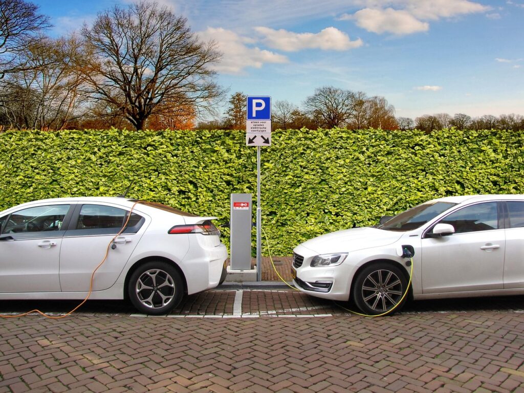 Mehrere Elektroautos stehen an Ladesäulen auf einem Parkplatz und zeigen den steigenden E-Auto Marktanteil in der EU – Foto: Joenomias / Pixabay