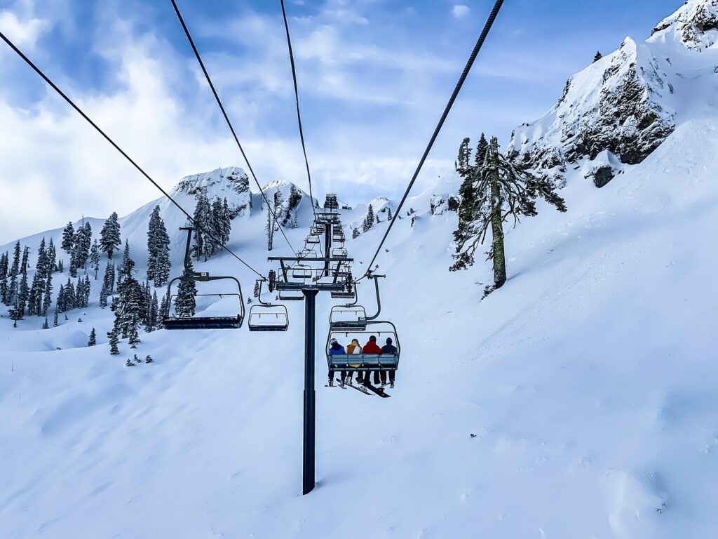 Ein Skipass hängt an einer Jacke vor verschneiten Pisten, passend zu den Skipasspreisen 2027 im Stundenvergleich – Foto: derwiki / Pixabay